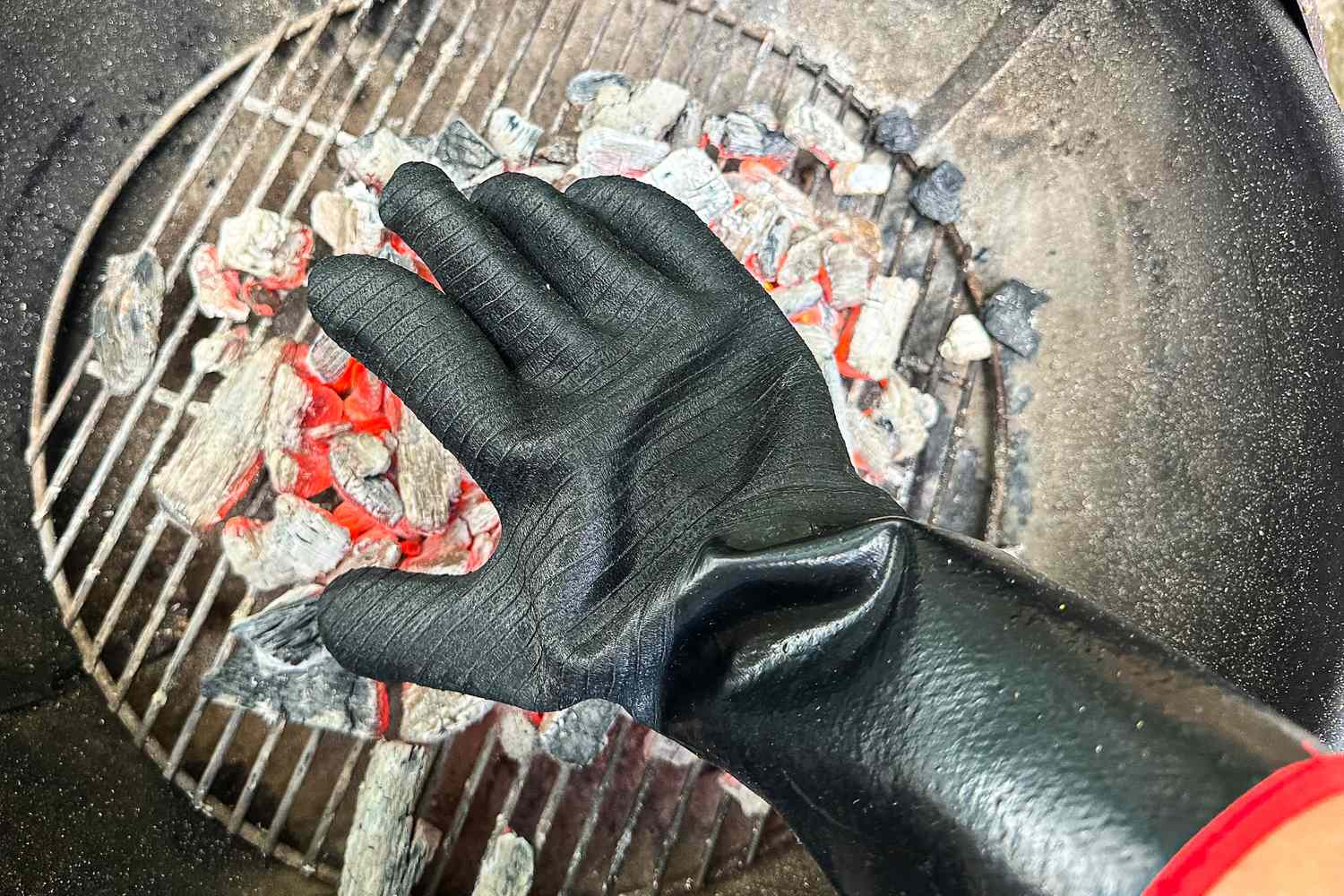 A person wears the Grill Armor Gloves BBQ Waterproof Gloves while holding their hand over hot coals