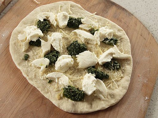 An assembled pizza on a wooden peel, ready to be baked.