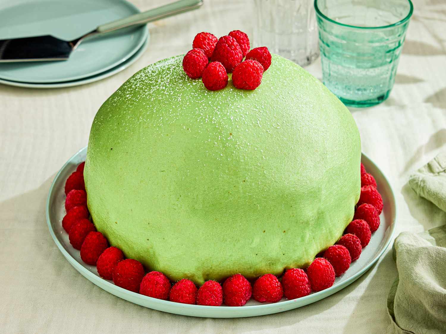 Princess cake garnished with raspberries on a white plate