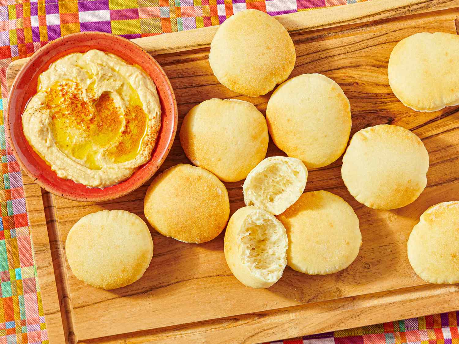 A wooden board with pita bread and a bowl of hummus