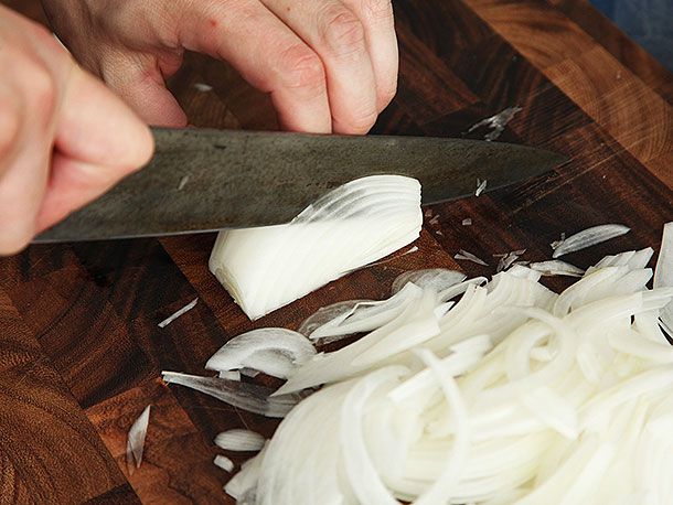 A knife midway through slicing into an onion.