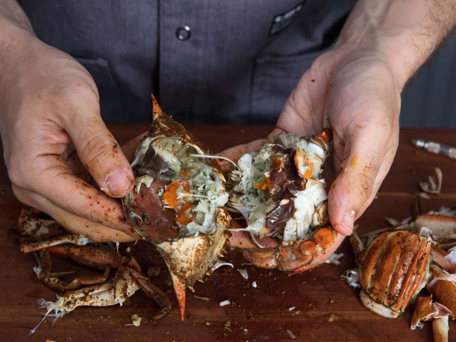 Pulling the body of a cooked crab in half to expose the innards