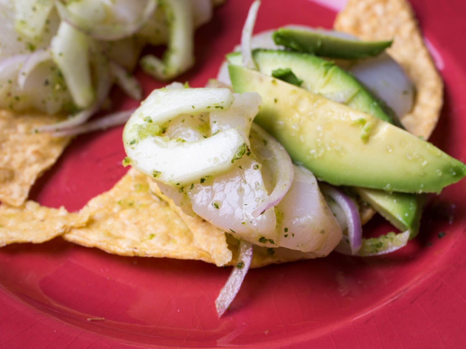 Tortilla chips topped with marinated seafood, red onion, and avocado.