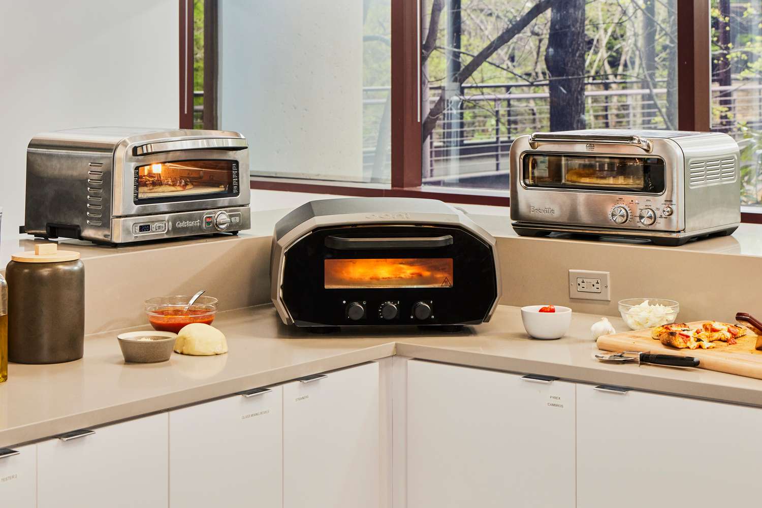 Three indoor pizza ovens on a kitchen countertop.