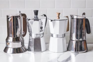 Four moka pots lined up on a kitchen counter