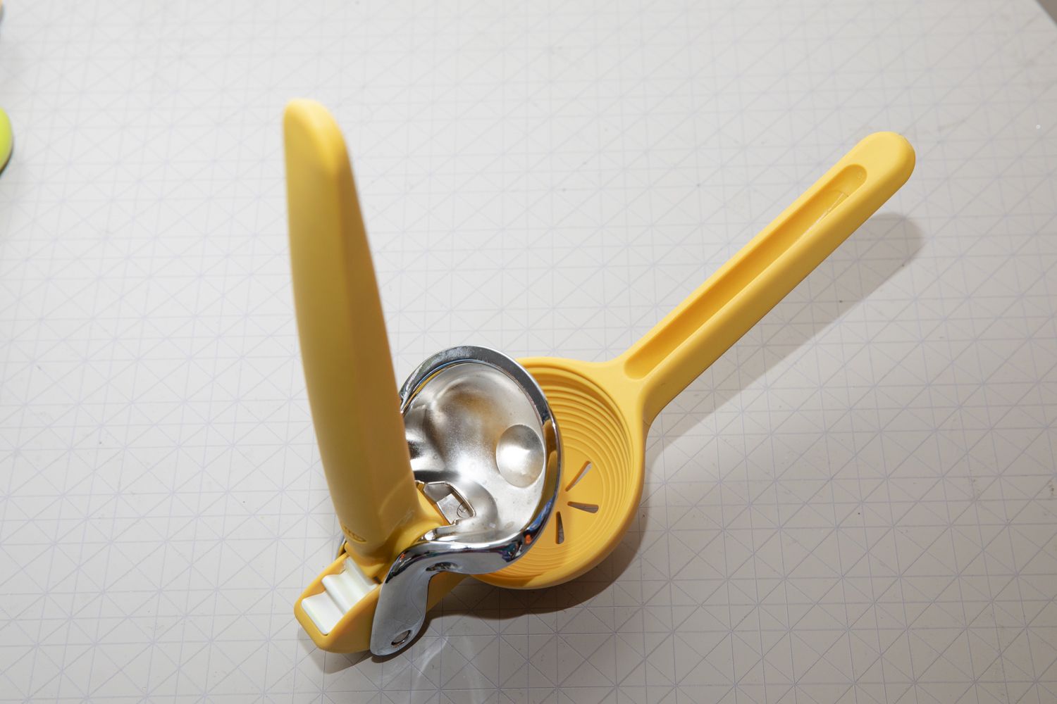 A yellow manual citrus juicer with its handle open