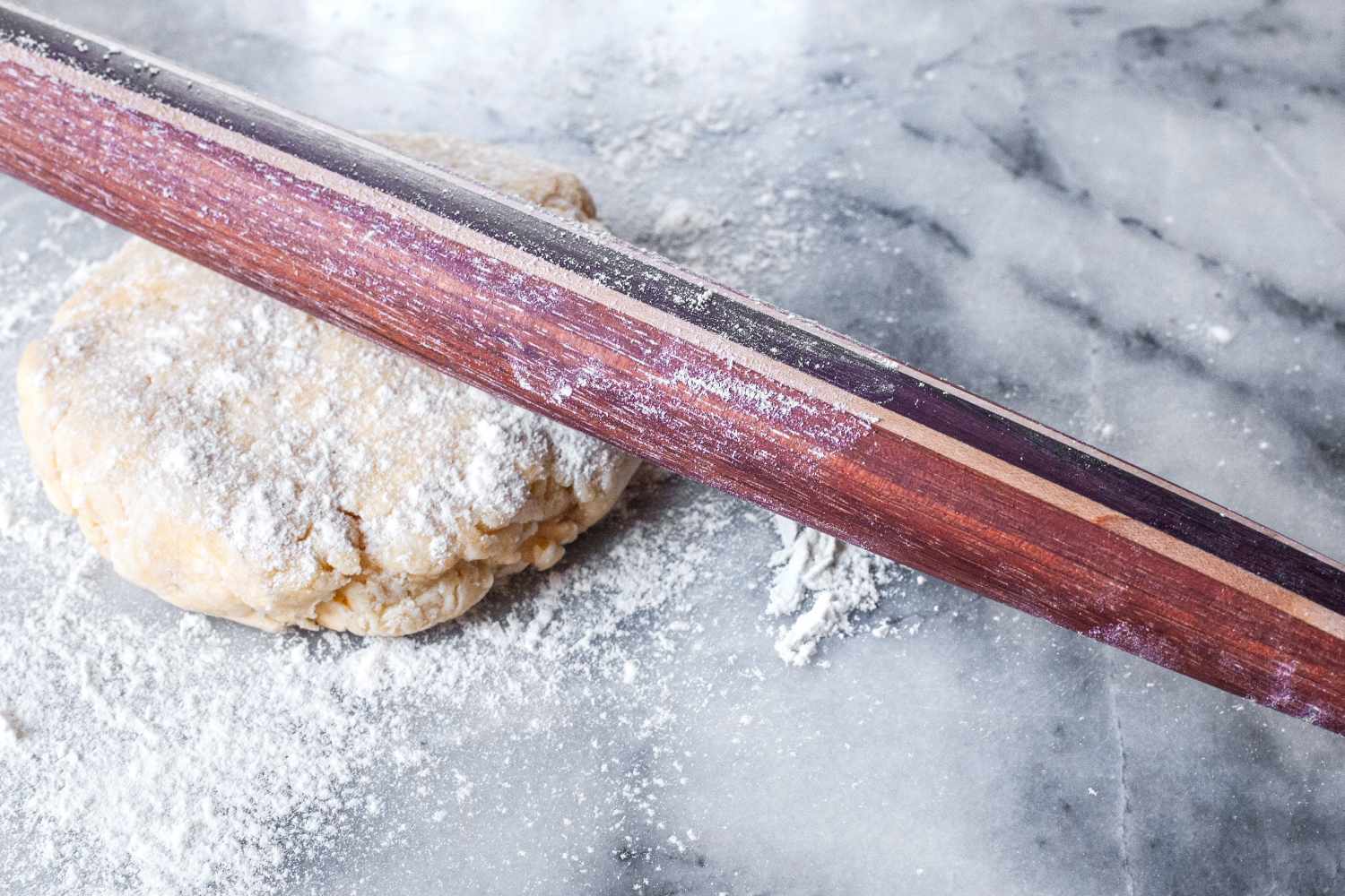 Earlywood French Rolling Pin on a lightly floured dough ball on a marble surface