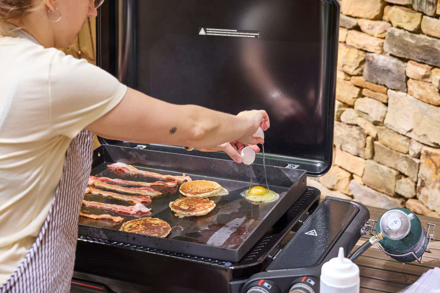 A person cracks eggs onto the Weber Slate 22 inch Rust-Resistant Tabletop Griddle