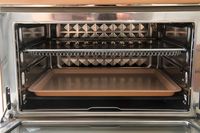 An open oven interior showing wire racks and a baking tray