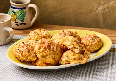 A plate of cheddar biscuits served on a striped tablecloth
