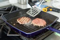 Two burgers being grilled using the Staub Enameled Cast Iron Grill Pan