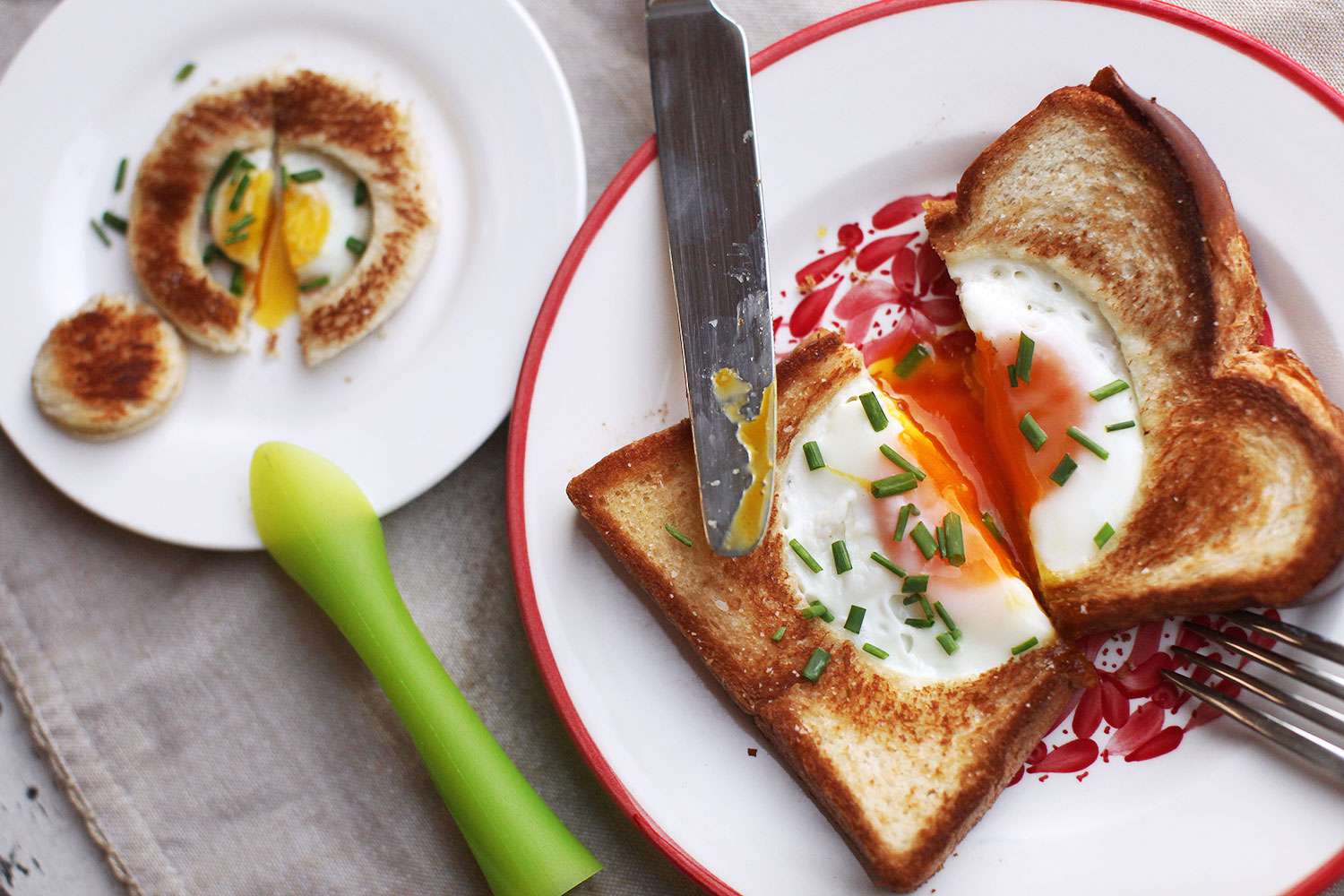 Adult and baby plated versions of egg-in-a-hole, both cut in half.