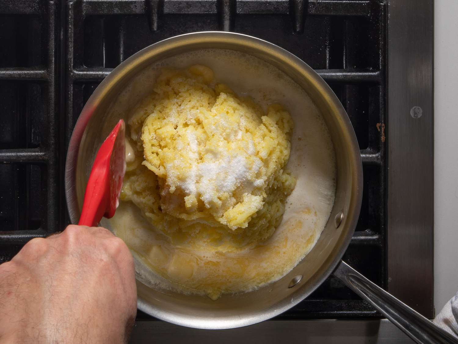 Folding hot cream and melted butter into mashed potatoes.
