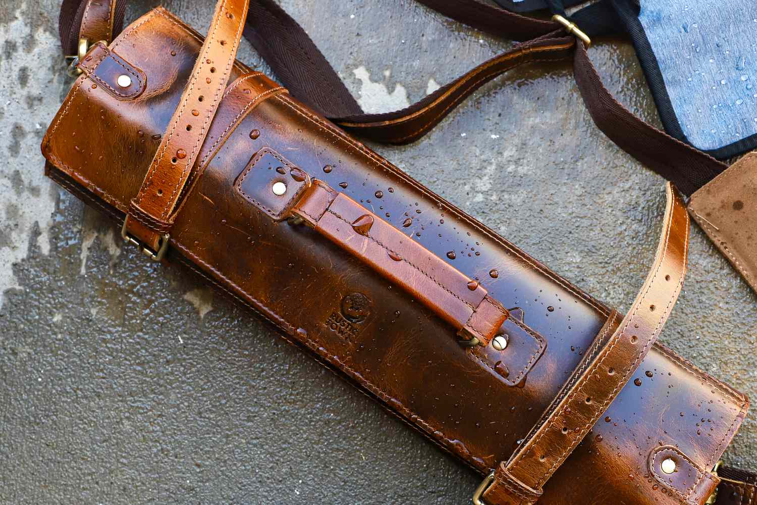 A Rustic Town Genuine Leather Chef Knife Roll with water droplets lying on a surface