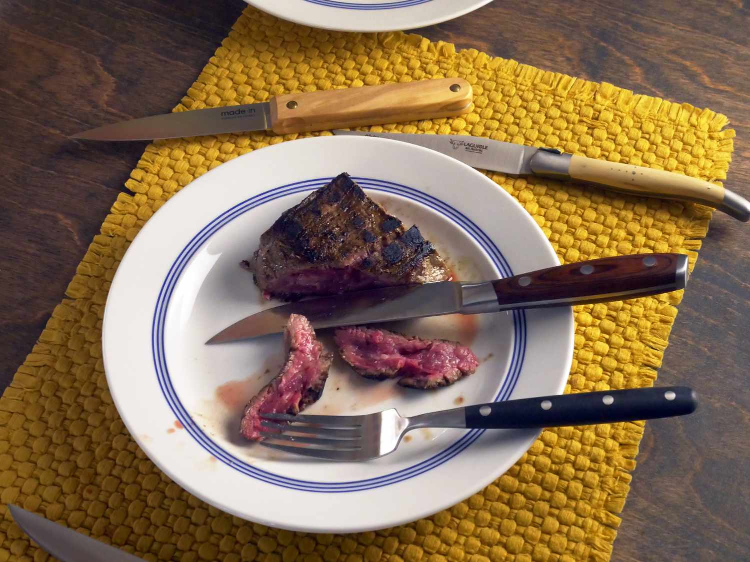 a piece of cut steak on a plate with a few steak knives