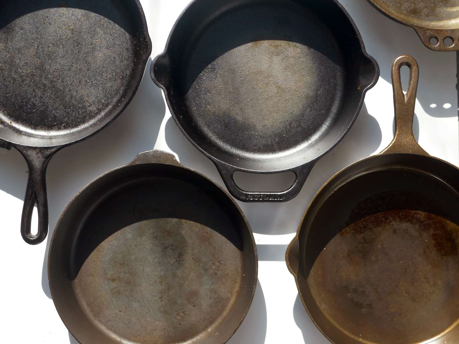 five cast iron skillets on a white surface