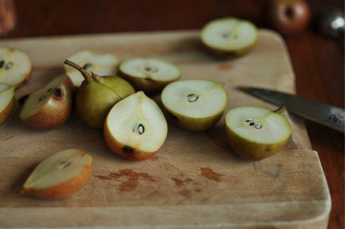 Halved seckel pears on a wooden cutting board.