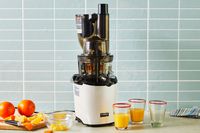 Kuvings REVO830 Whole Slow Juicer displayed with oranges and orange juice