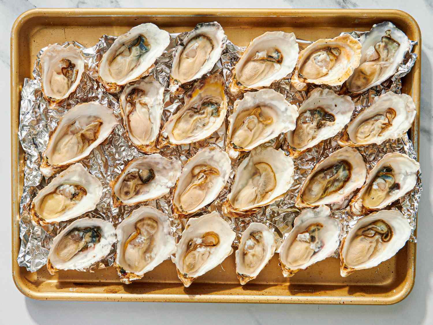 Roasted oysters arranged on a baking tray lined with foil
