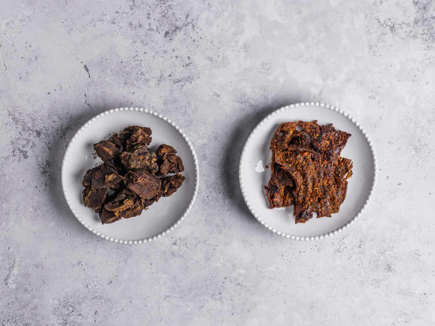 Dried Kilishi and tinko in two white bowls on a marbled grey background