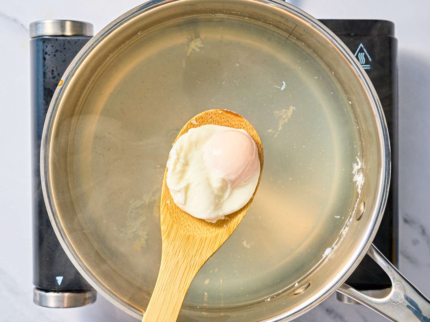 egg lifted out of pot with a slotted wooden spoon
