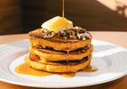 Stack of pancakes with pecans butter and syrup on top