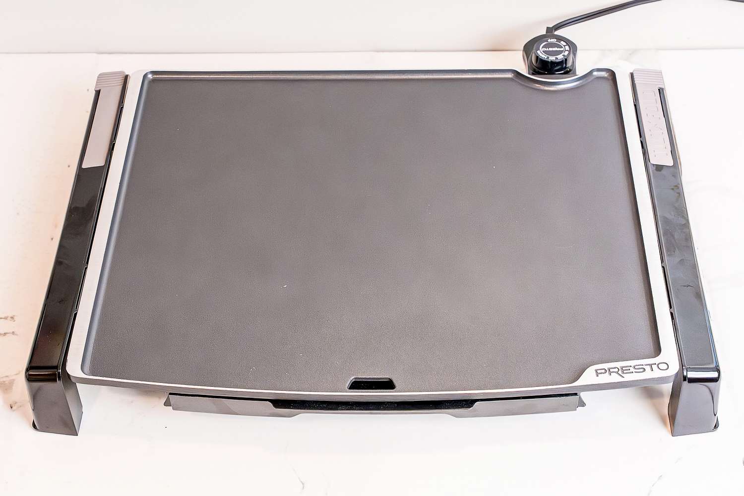 The Presto Tilt-N-Fold electric griddle on a white marble countertop