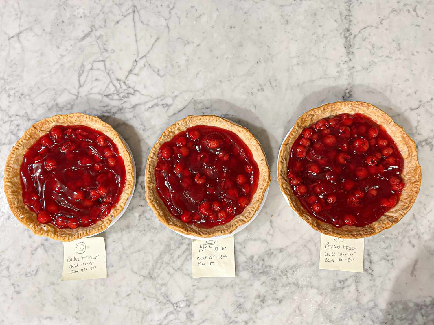 Three cherry pies with different pie crusts each labeled with the flour used for the crust test