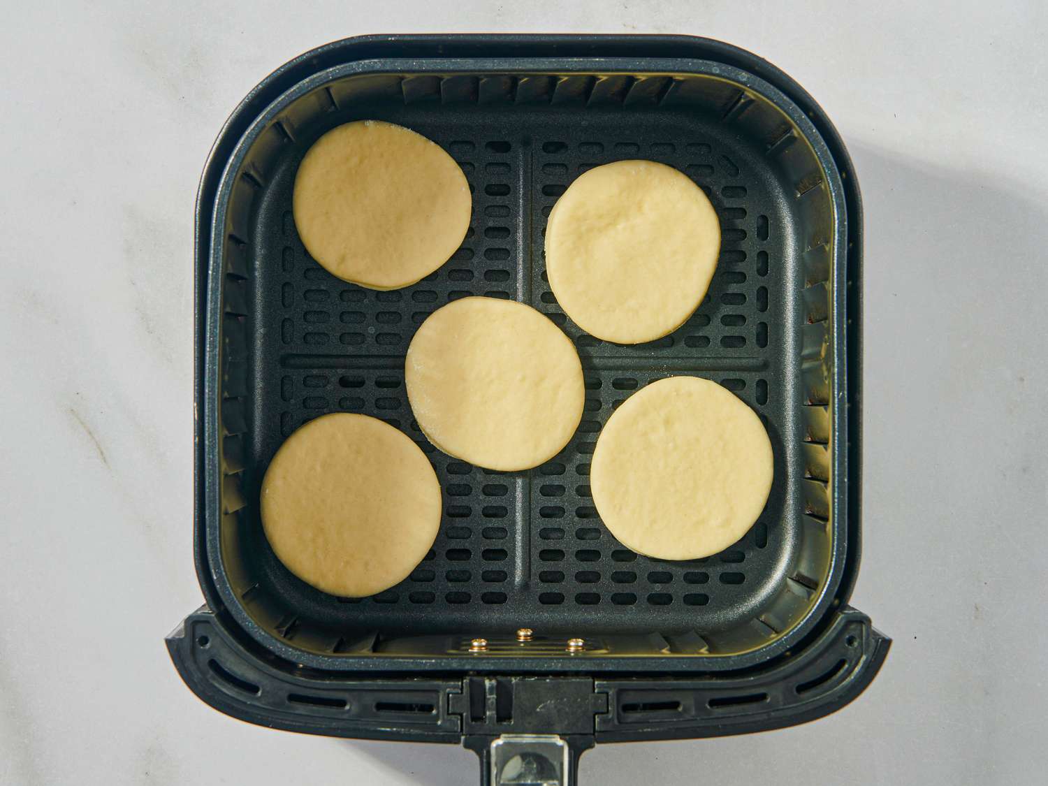 Pita rounds arranged in an air fryer basket