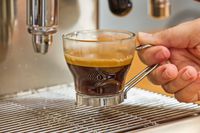 A close-up of a hand removing an espresso cup from the Lelit MaraX Espresso Machine PL62X-120