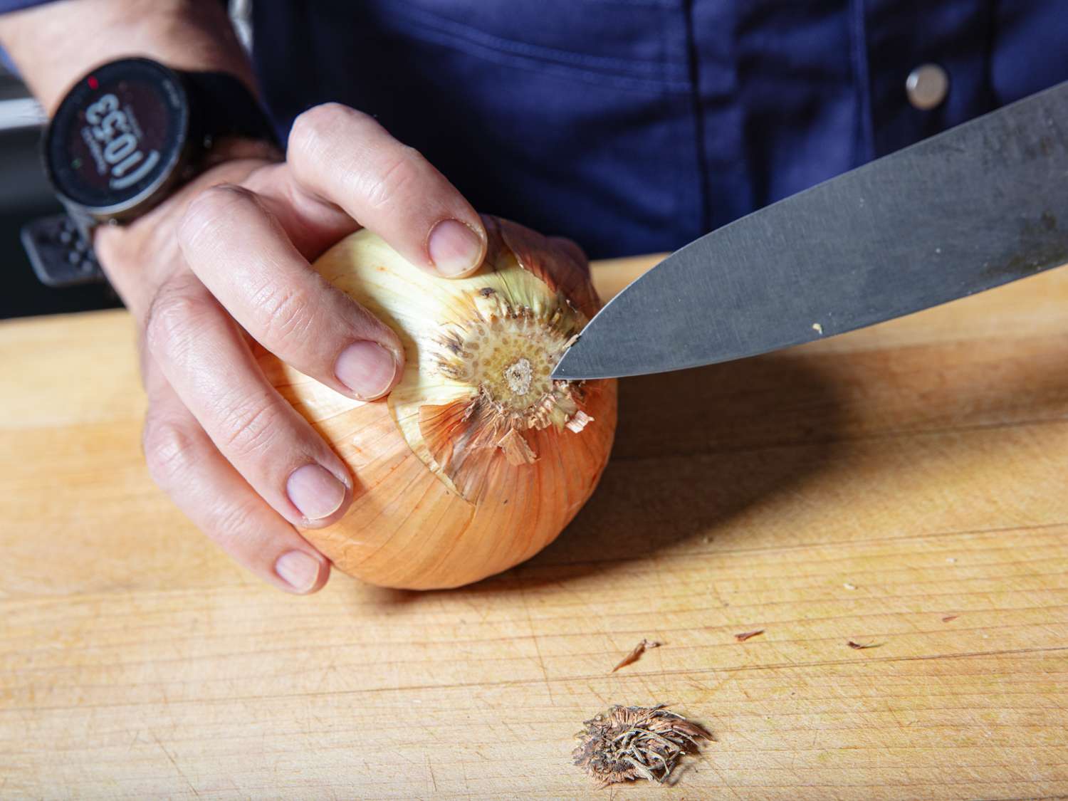 Trimming the root end off an onion before peeling.