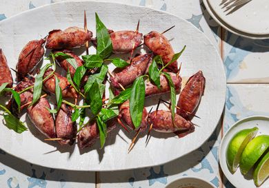 Platter of grilled stuffed squid with garnish displayed on a table with lime wedges and sauce
