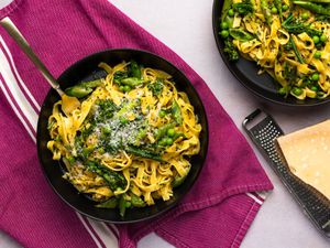 Pasta Primavera served inside a dish, drizzled with olive oil, sprinkled with freshly ground black pepper, and served with grated Parmigiano-Reggiano 