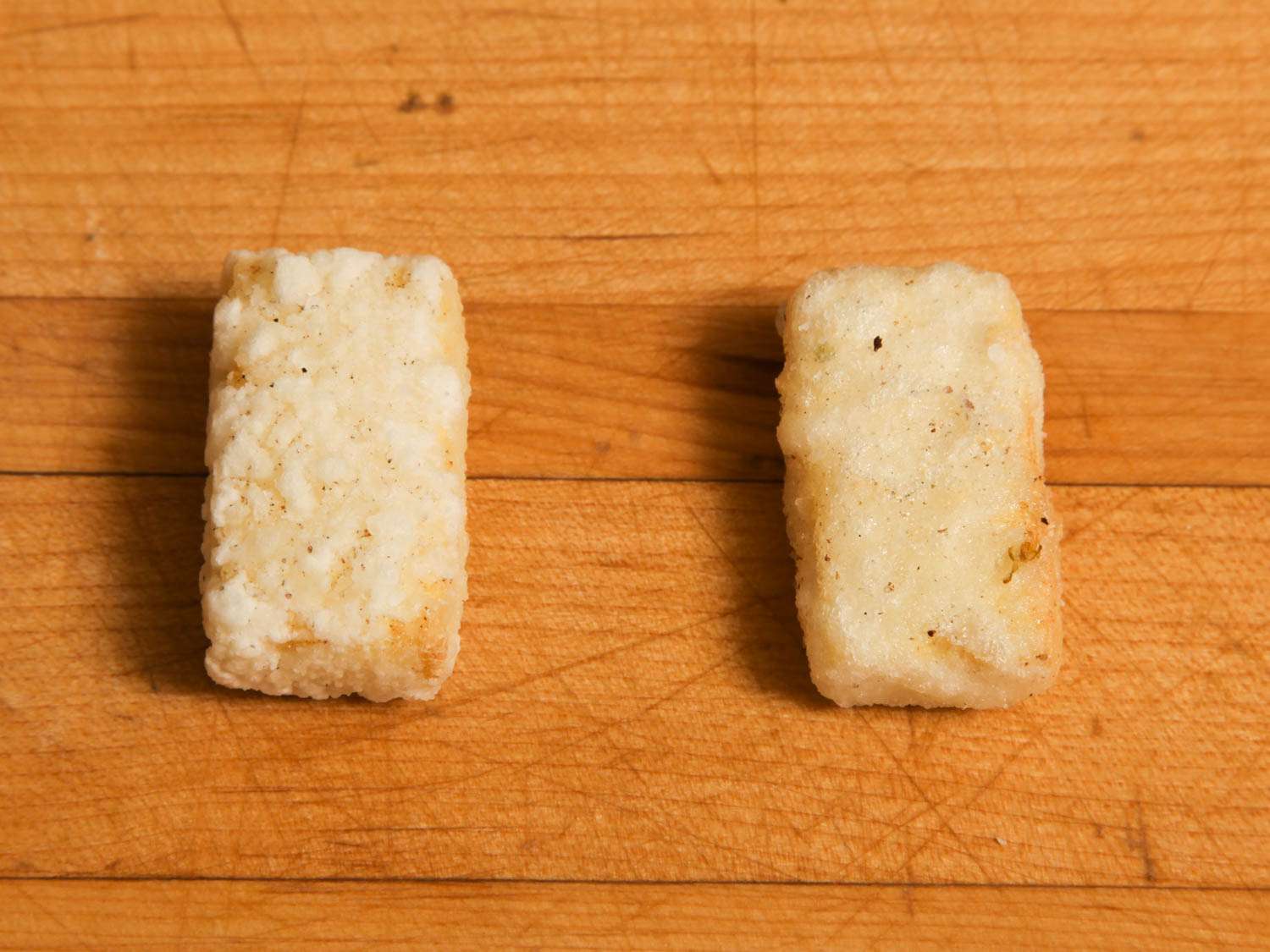 Testing samples of crispy fried tofu on a wooden surface.