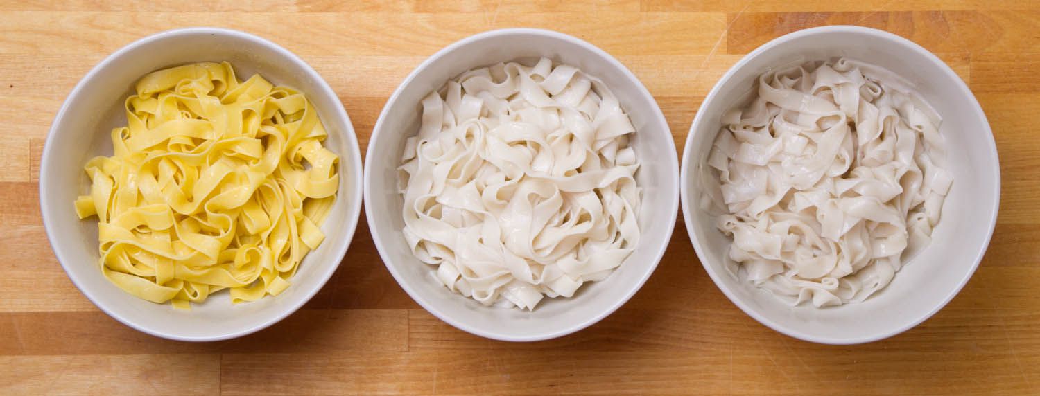 Overhead shot of three bowls of pasta, made with an egg yolk dough, an egg white dough, and a water-and-flour dough.