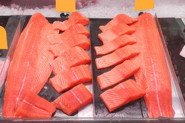 Slices and fillets of salmon arranged on display in a storefront or market counter