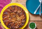 Overhead of a richly-golden French onion soup tarte tatin on a bright-yellow plate 