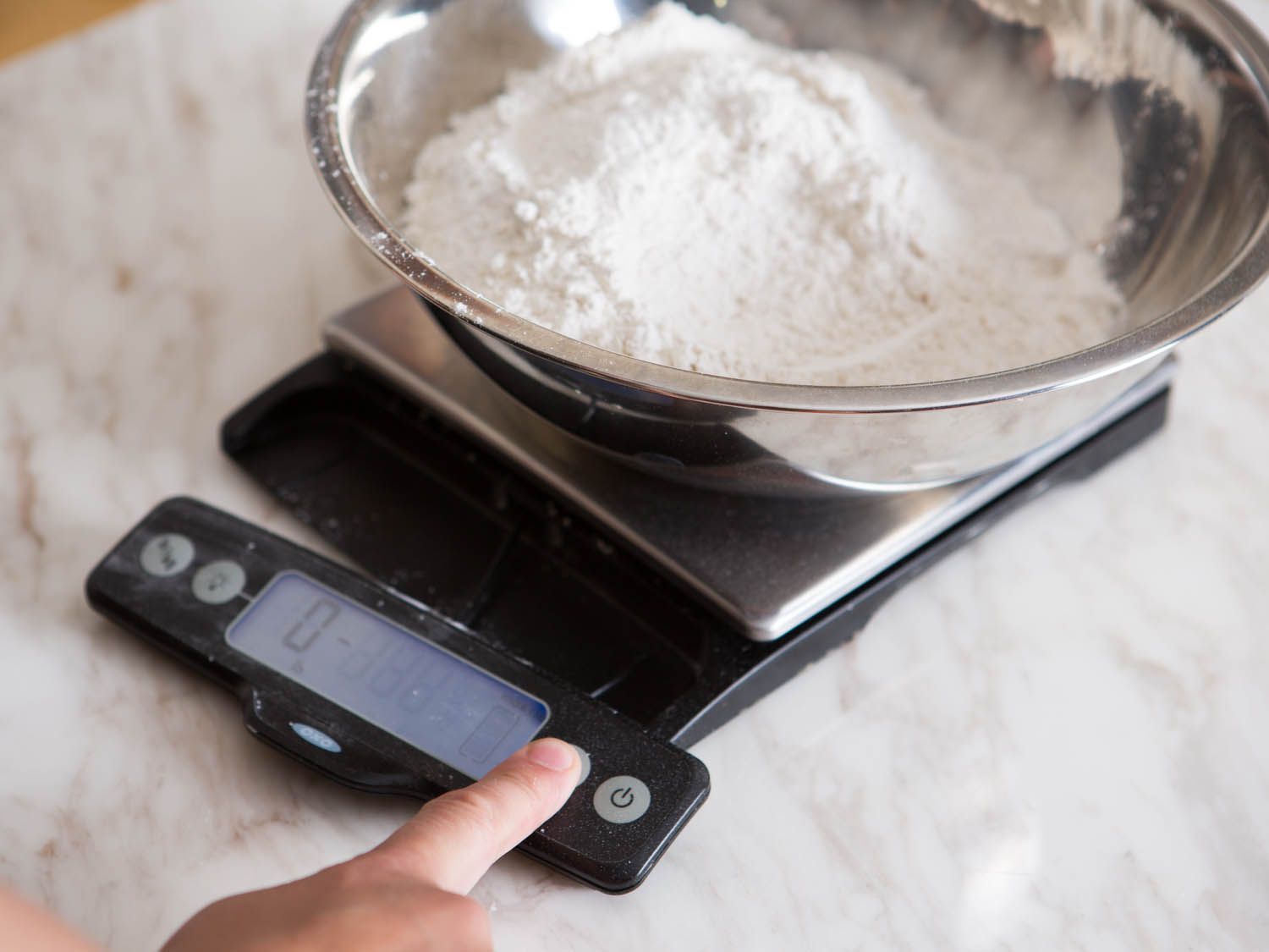 The scale is tared with the flour so that another ingredient can be added and measured accurately.