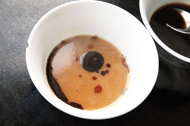 A bowl of tonkotsu ramen broth with drops of mayu black garlic oil. 