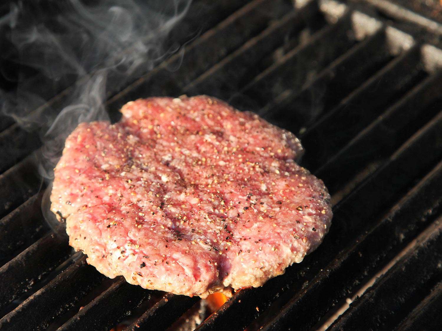 A burger patty cooking on a grill.