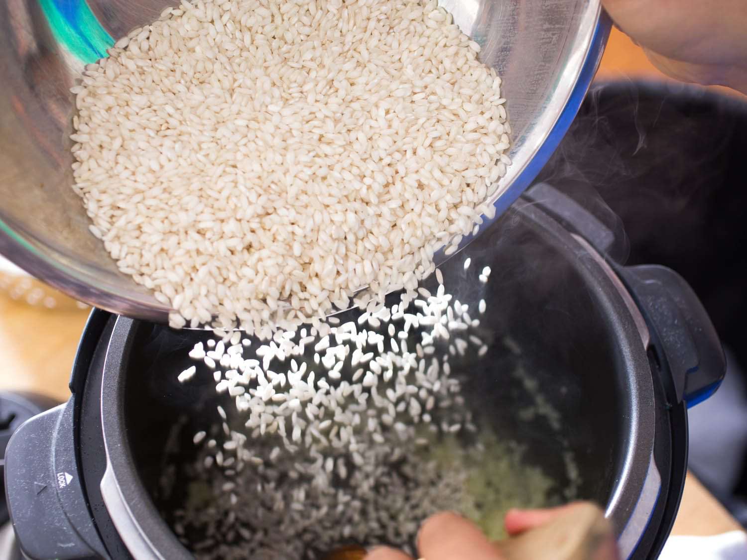 Rice being poured into pressure cooker for risotto.