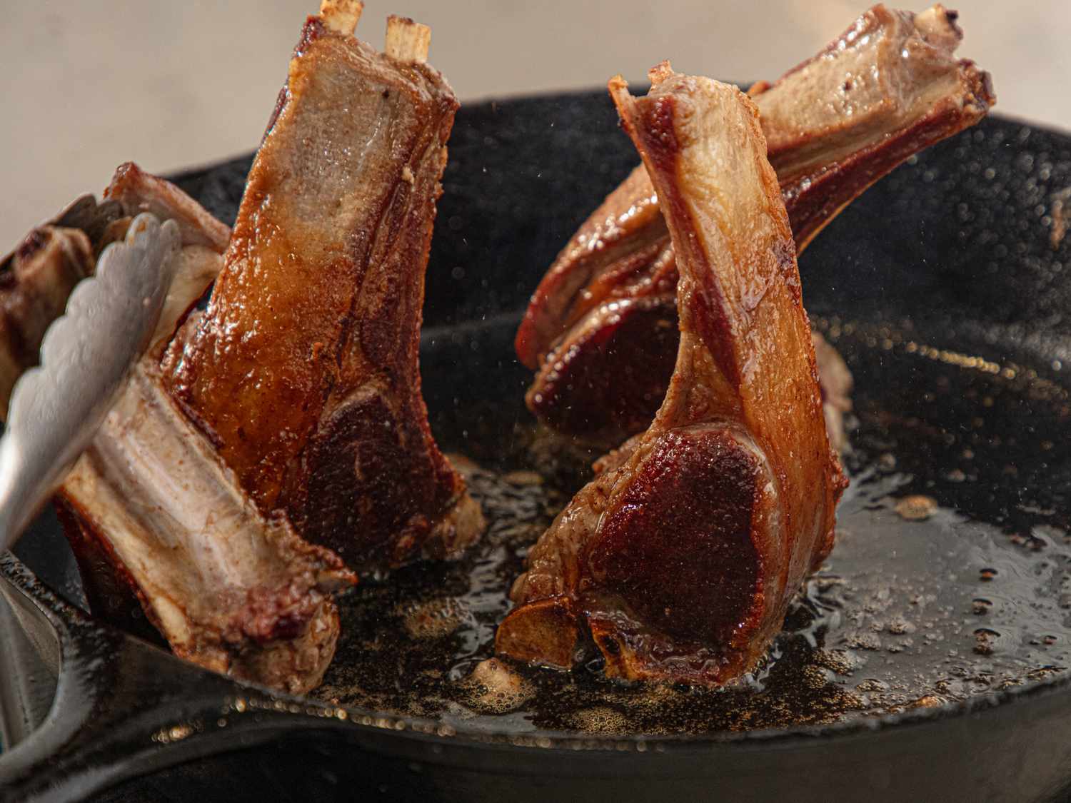 Cooking lamb chops in a skillet searing them on high heat