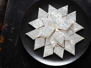 Overhead view of kaju katli, artfully arranged on a black plate.