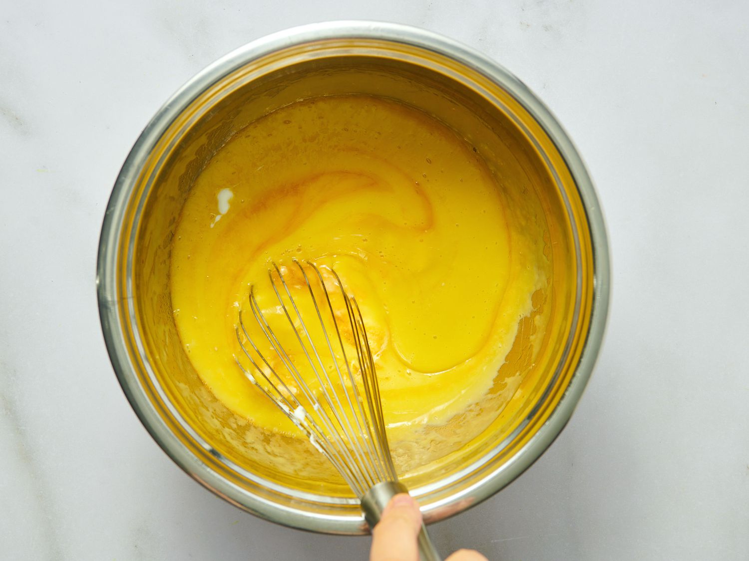 Mixing batter in a metal bowl with a whisk