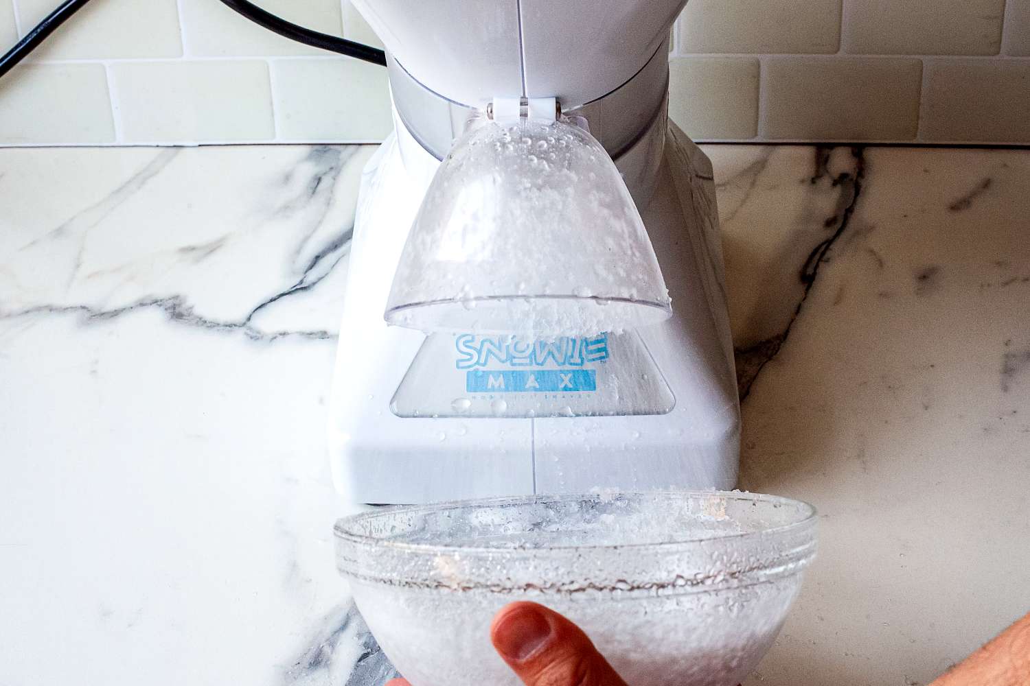 Snowie Little Snowie Max Snow Cone Machine in use, dispensing shaved ice into a bowl