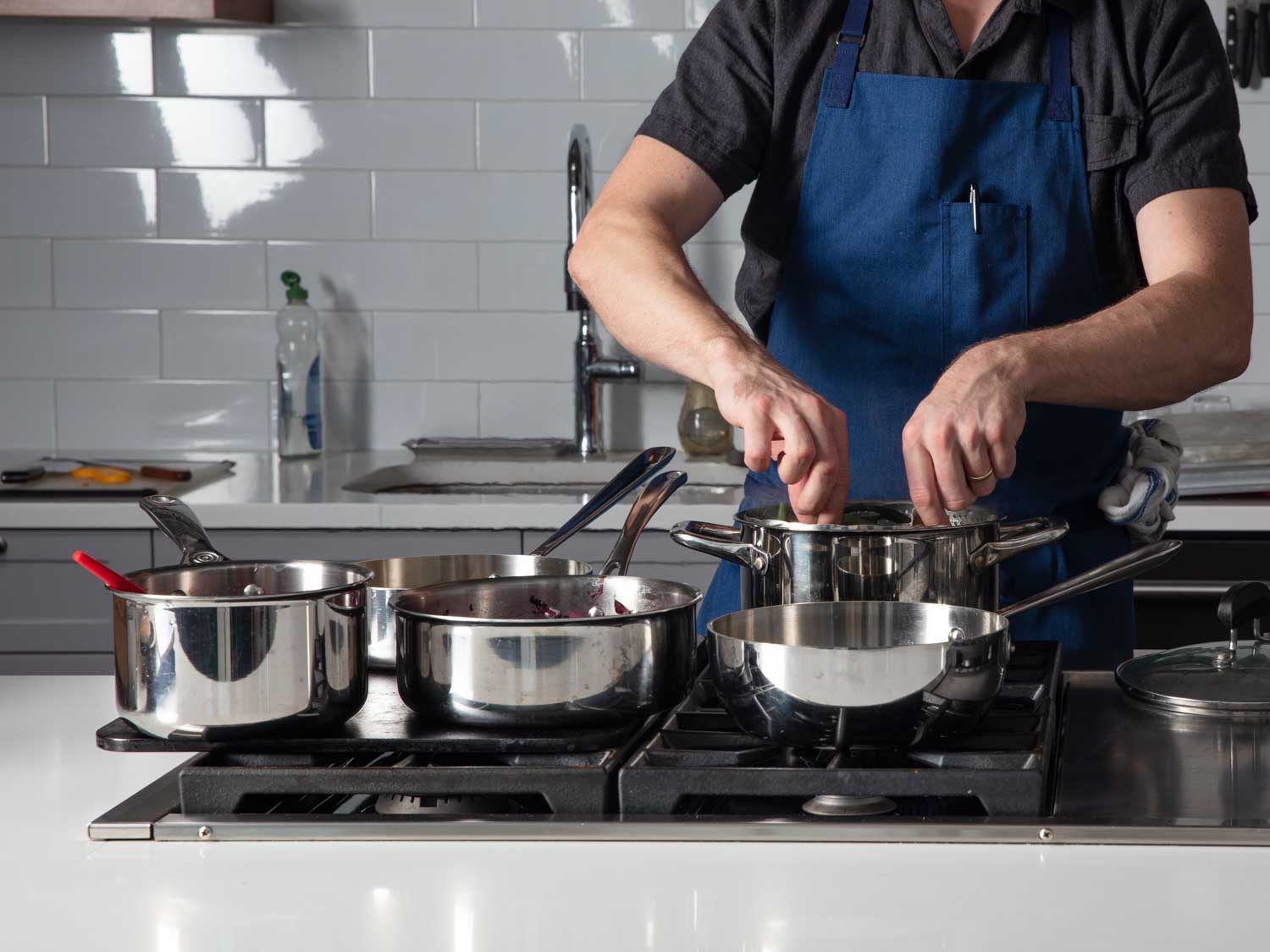 Front view of Baking Steel set-up with three saucepans set on it, and two pots on remaining free burners.