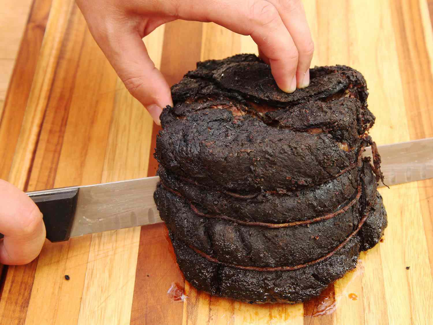 The smoked chuck roast is sliced in half on a cutting board.