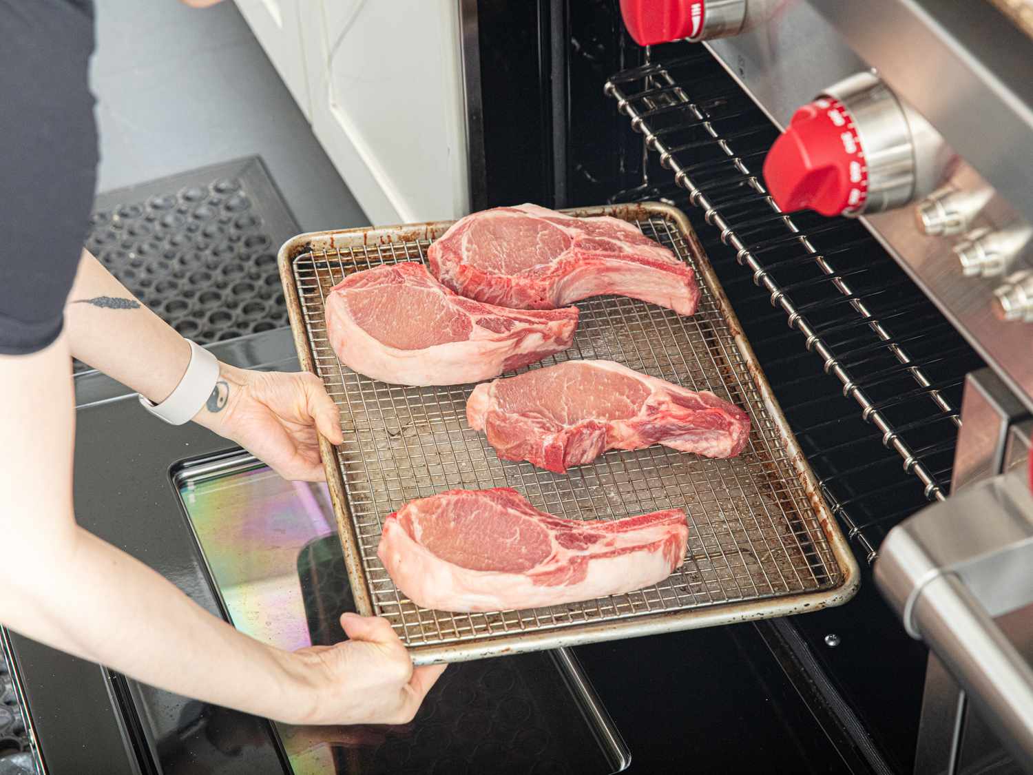 Side view of putting pork chops in oven 