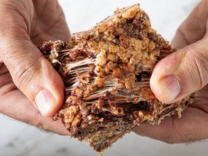 Hands pulling apart a sticky textured crispy rice treat