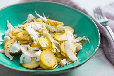 Summer squash salad with goat cheese, fennel, and dill, served in a shallow turquoise bowl.